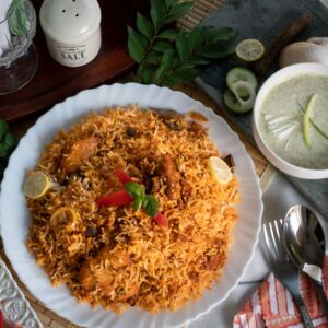 Top view of traditional Pakistani biryani, raita, and salad, beautifully arranged on a table.
