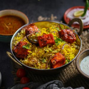 Delicious Indian paneer biryani with sides, showcasing vibrant spices and flavors. Perfect meal inspiration.
